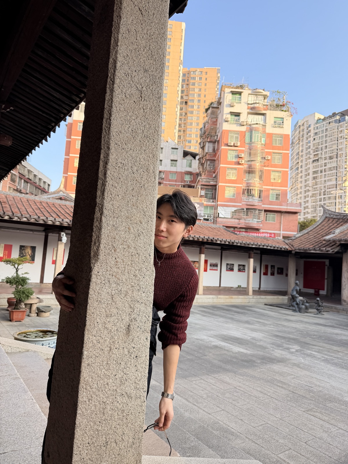 Garrett Xu leaning around a stone pillar in a courtyard